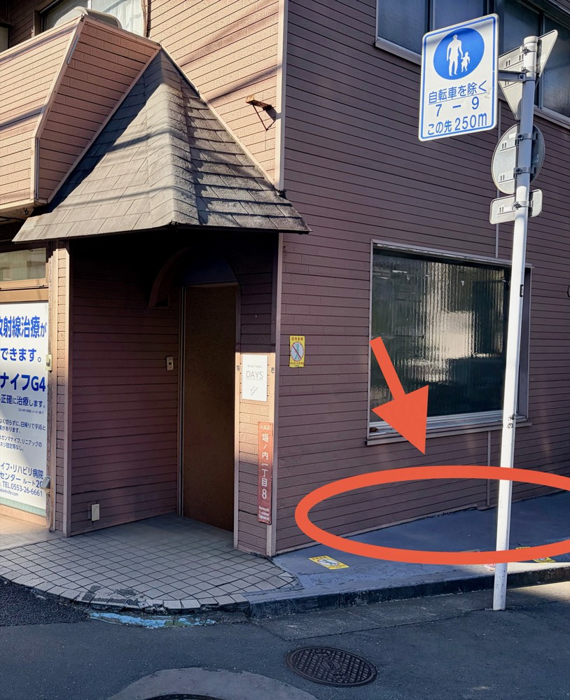 DAYS方南町店の建物入口右手、電柱手前にある自転車を停められる一段高くなったコンクリート部分を赤い印で示した写真